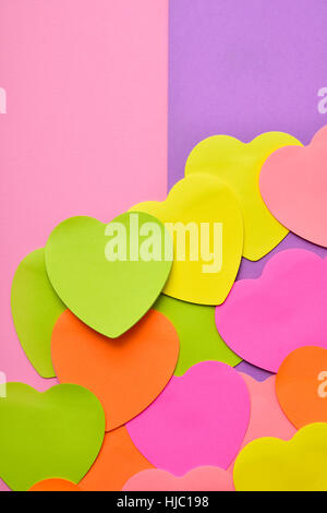 some heart-shaped sticky notes of different colors with a blank space, on a half pink and half violet background Stock Photo