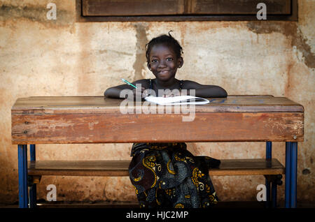 School Background: Proud African Schoolgirl Sitting In Her Desk Smiling Stock Photo