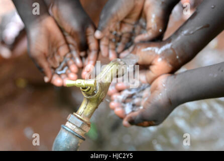 Hands of African Children Cupped under Tap Drinking Water Malnutrition. Hands of African black boys and girls with water pouring from a tap. It affect Stock Photo