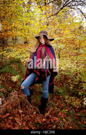 Young teenage girl standing in a forest in Autumn surrounded by pretty Autumnal colors Stock Photo