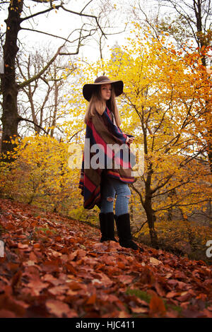 Young teenage girl standing in a forest in Autumn surrounded by pretty Autumnal colors Stock Photo