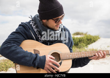 Young man playing acoustic guitar on beach, Western Cape, South Africa Stock Photo