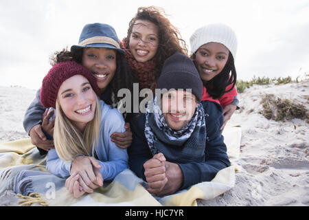 Portrait of young adult friends lying on top of each other on beach, Western Cape, South Africa Stock Photo