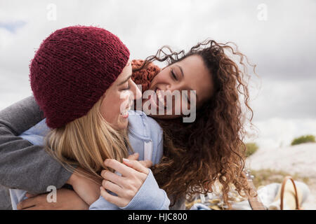 Two young female friends hugging at beach, Western Cape, South Africa Stock Photo
