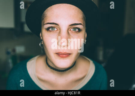 Head and shoulder portrait of blue eyed young woman in trilby