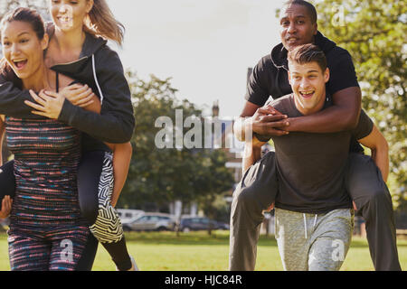 Men and women having fun training in park, having piggy back  race Stock Photo