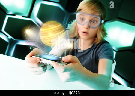 Boy with hand held computer staring at digital spinning planet Stock Photo