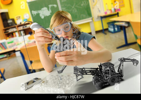 Boy with digital pen and 3D model of excavator in classroom Stock Photo