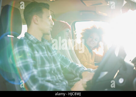 Three young adult friends driving in sunlit car Stock Photo