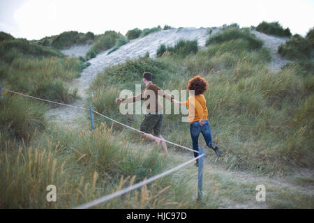 Couple running on grassy dune Stock Photo