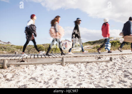 Young adult friends on the move on beach boardwalk, Western Cape, South Africa Stock Photo