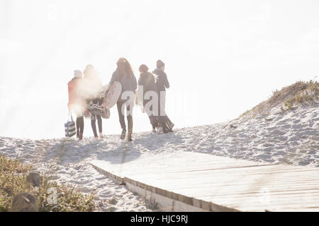 Rear view of young adult friends strolling on sunlit boardwalk at beach, Western Cape, South Africa Stock Photo