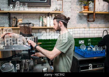 Young male barista preparing coffee in cafe kitchen Stock Photo