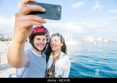 Young moped couple taking selfie on harbour, Split, Dalmatia, Croatia Stock Photo