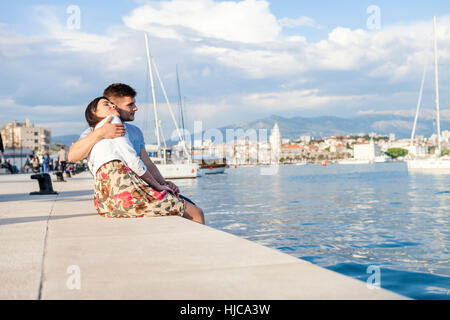 Young couple sitting on harbour, Split, Dalmatia, Croatia Stock Photo