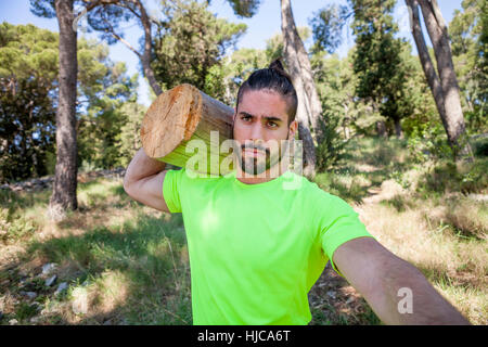 Young man doing weightlifting training with log in forest, Split, Dalmatia, Croatia Stock Photo