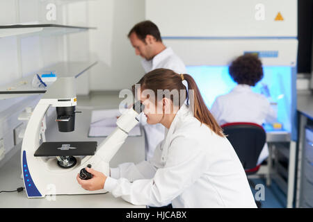 Scientist in laboratory looking through microscope Stock Photo