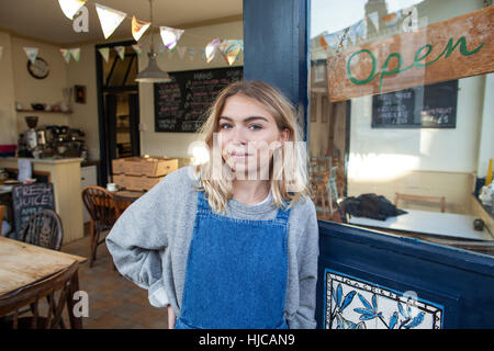 Portrait of young woman standing in doorway of cafe Stock Photo