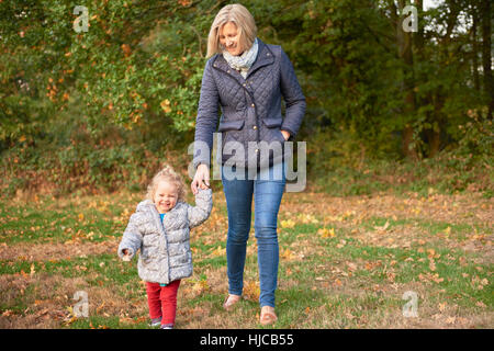 Senior woman strolling with toddler granddaughter in autumn park Stock Photo