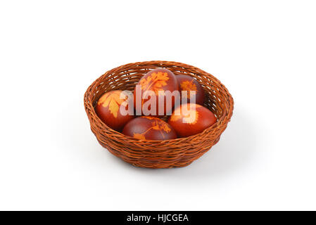 basket of Easter eggs decorated with fresh leaves and boiled in onion peels on white background Stock Photo