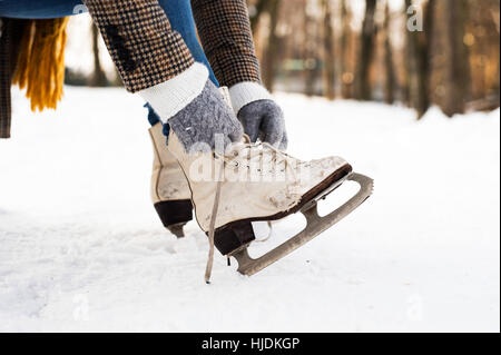 Unrecognizable woman in winter clothes putting on old ice skates Stock Photo