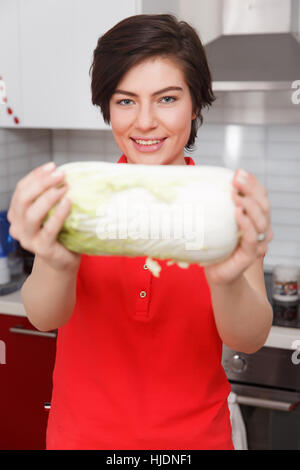 Woman holding cabbage in kitchen Stock Photo