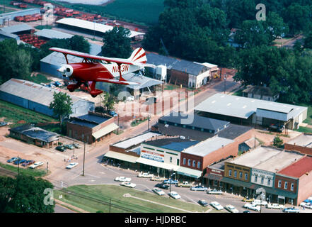 A Pitts Special biplane flies over the Main Street of Plains, Georgia - the hometown of President Jimmy Carter. - Stock Photo