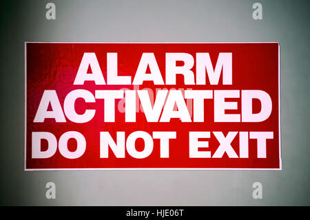 A red sign on a white metal background that says: ALARM ACTIVATED. DO NOT EXIT. Concept of mystery,adventure,suspense. Stock Photo