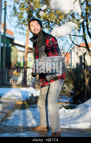 bearded man shoveling snow wearing a shirt and a west Stock Photo