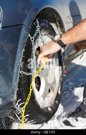 Man mounting snow chains on car wheels Stock Photo