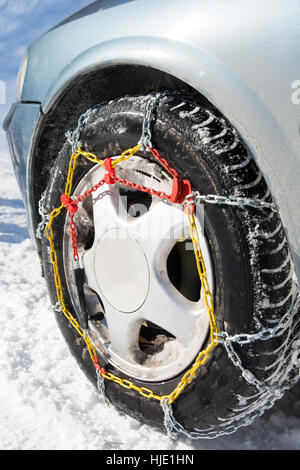 Snow chains mounted on car wheels on winter day Stock Photo