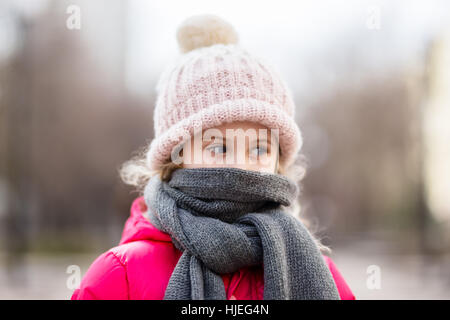 Closeup portrait of cute baby girl wearing knitted hat and winter jacket outdoors Stock Photo