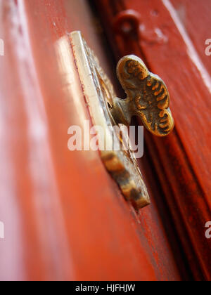 Extreme closeup of a fancy antique brass doorknob on an old red door. Stock Photo