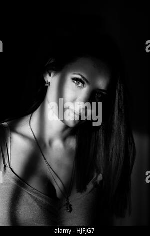 Young attractive cute girl dramatic portrait. Black and white photography. Low key. Stock Photo