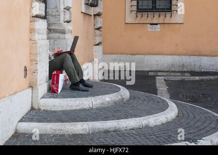 A man sitting on the steps and working with laptop, Rome, Italy, Europe Stock Photo