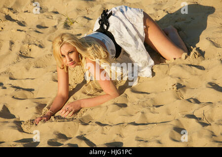 Beautiful long haired blonde young woman in a summer dress on the beach. Stock Photo