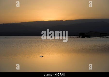 Sunset in Dallol, Danakil Depression salt flats or salt lake, view of the pumping station to extract salt and mountains behind Stock Photo