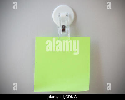 Light green post it clip by clip magnet on gray refrigerator background. Stock Photo