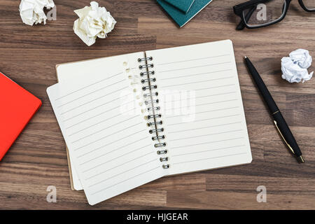 Notebook on office wood desk with pen and crumpled paper ball Stock Photo