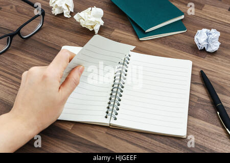 Office desk with hand tearing paper from notebook and crumpled paper ball Stock Photo