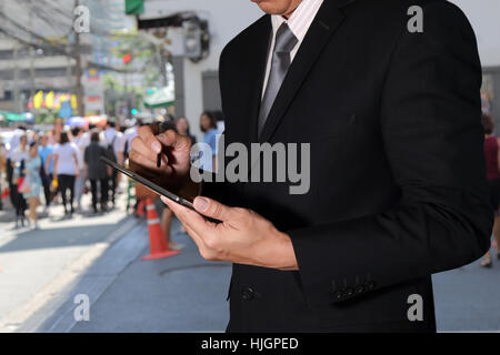 Young BusinessMan using Tablet device on blurred abstract  outdoor shopping background as Working Lifestyle Concept. Stock Photo