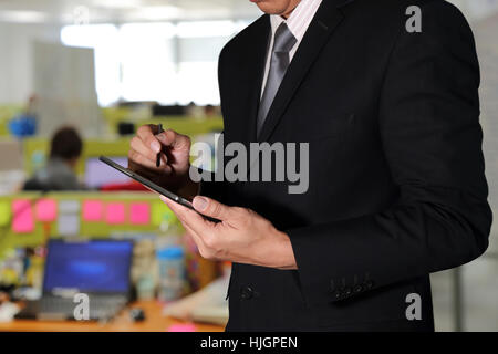 Business Man using Tablet device on blurred abstract the workplace background as Working Concept. Stock Photo