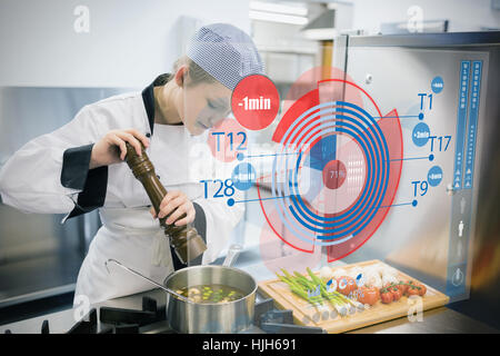 Chef seasoning soup and using futuristic interface showing time Stock Photo