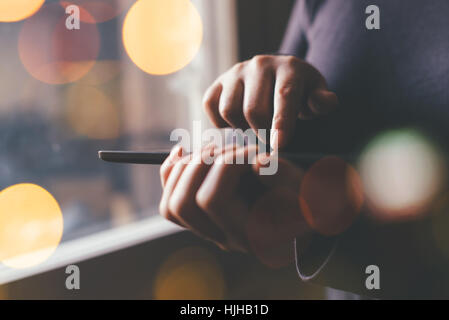 Woman using digital tablet computer for internet browsing, young adult female standing by the window Stock Photo