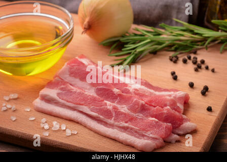 Still life with sliced raw bacon, olive oil, spices and herbs Stock Photo