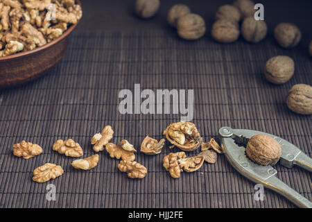 Walnut kernels and whole walnuts in brown ceramic bowl. Healthy organic food concept. Selective focus Stock Photo