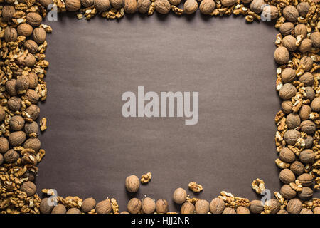 Frame made of walnuts on dark brown paper background. Space for your text Stock Photo