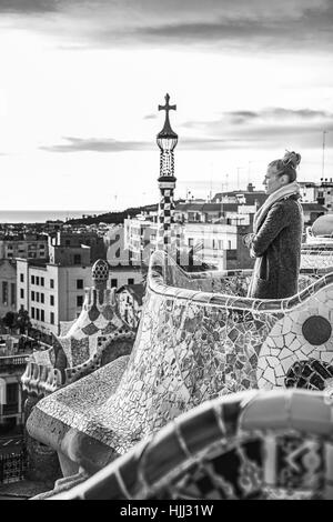 Barcelona signature style. modern tourist woman in coat at Guell Park in Barcelona, Spain looking into the distance Stock Photo