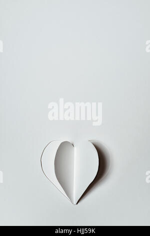 a heart cut out in an off-white cardboard, with a blank space above it Stock Photo