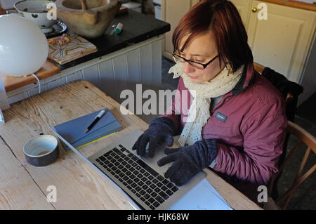 A woman works at home from her cold kitchen. Stock Photo
